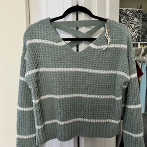 A teal v-neck sweater with crisscross strings in the back. It’s never been worn